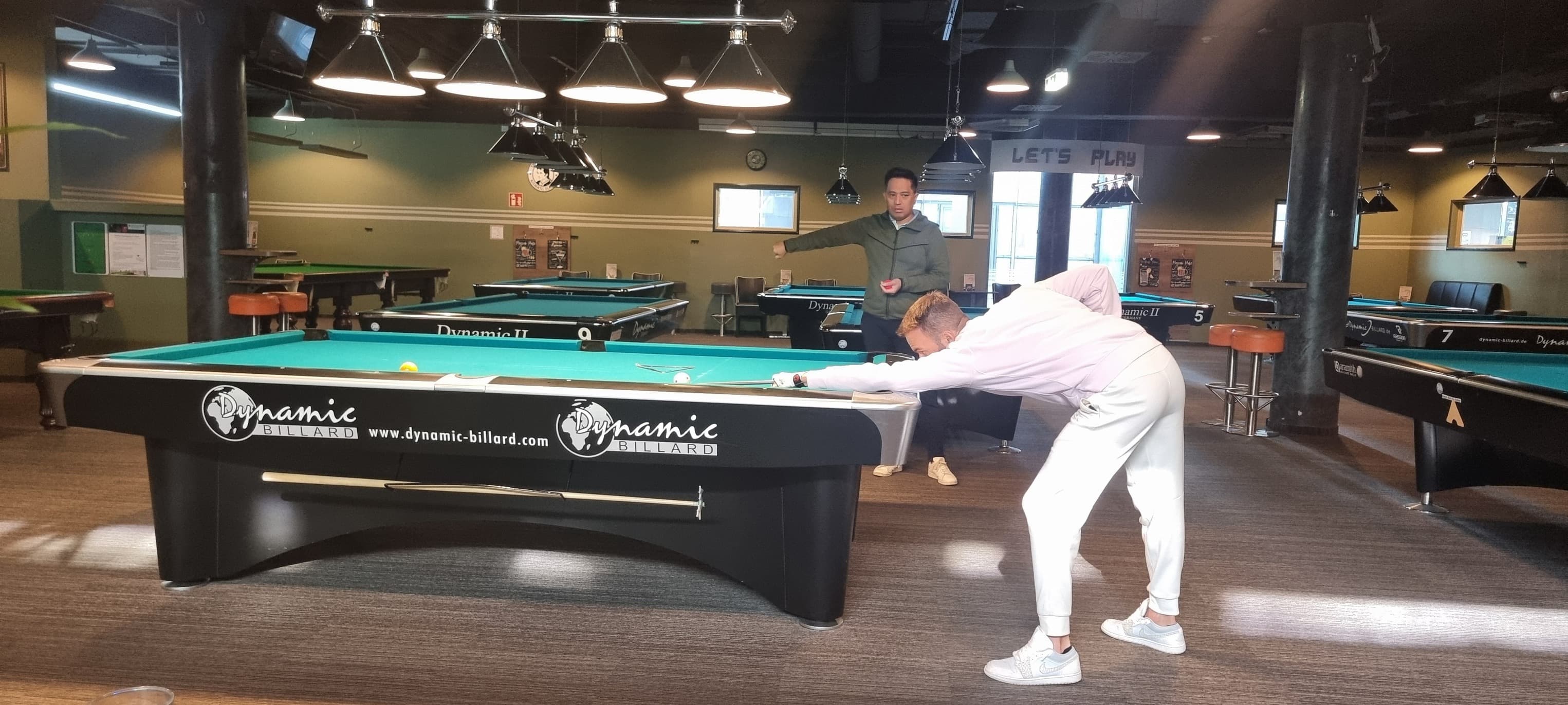 A player playing pool in a dark billiard room.