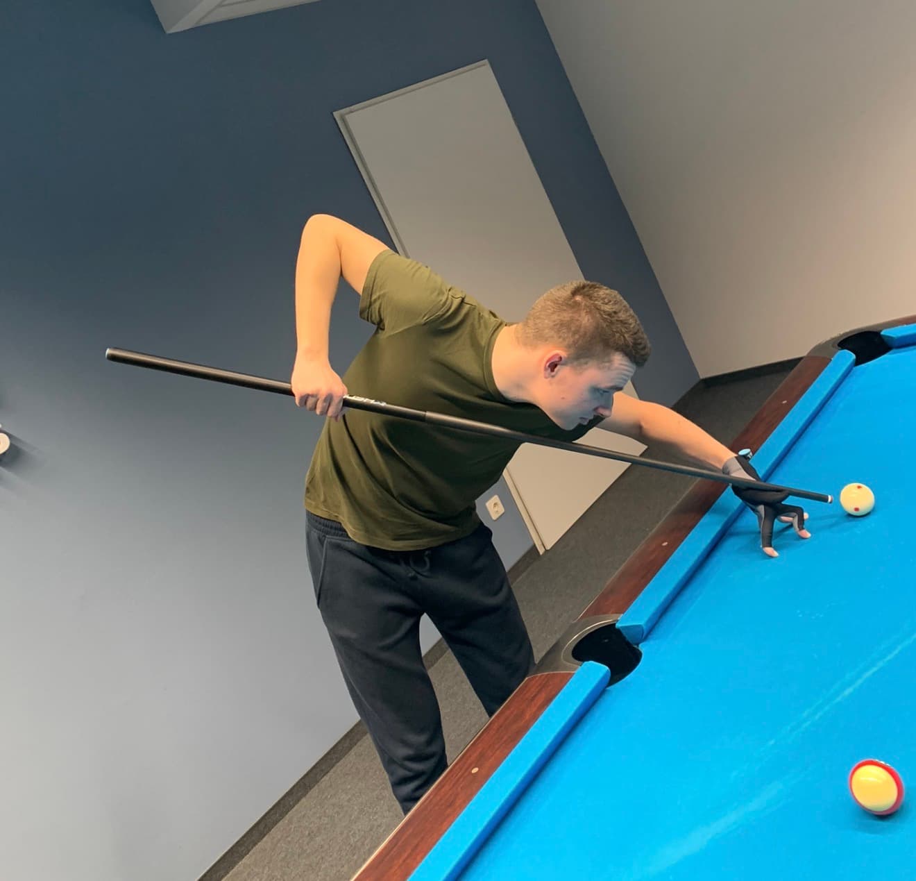 A player is playing pool at a blue table.
